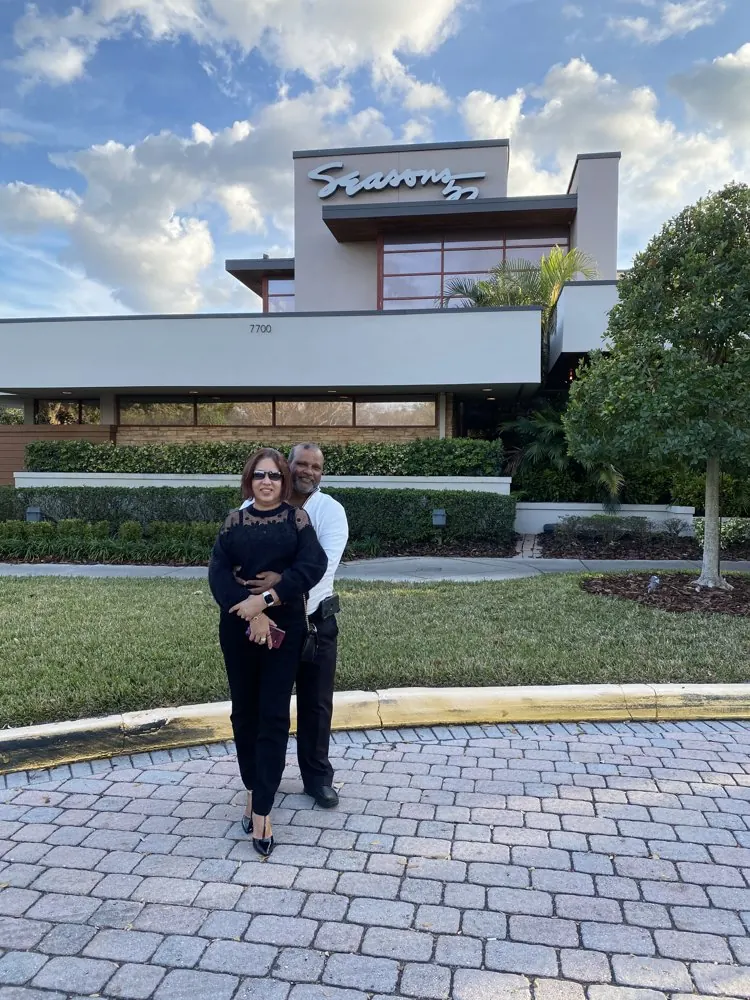 Kris Persaud and his wife outside a restaurant, wide view