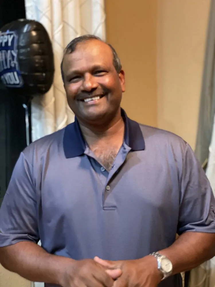 Kris Persaud smiling, wearing a navy polo shirt