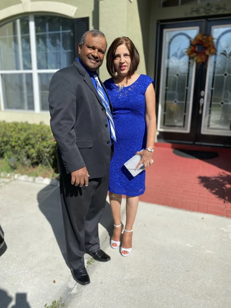 Kris Persaud in a suit with his wife at a formal event