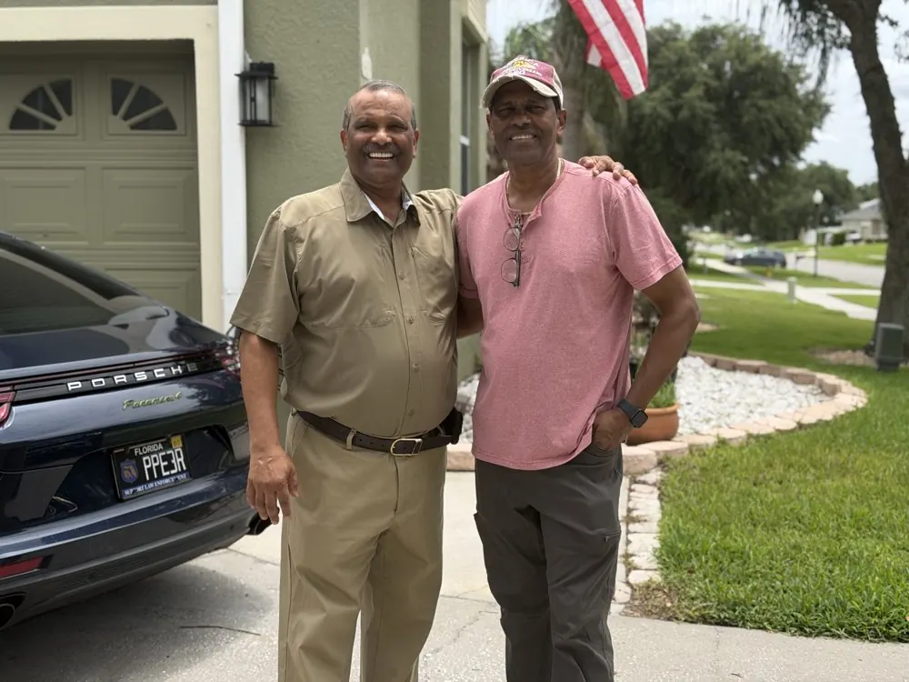 Kris Persaud with a friend outside a home